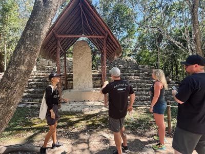 Kat showing guests a carved stone at the Coba ruins